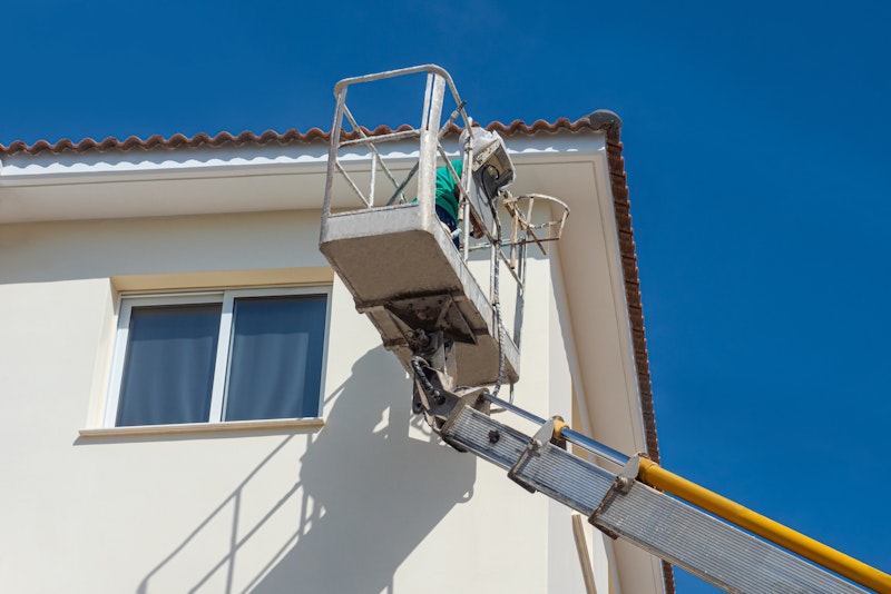 A man painting the exterior of a 3-story townhome in Katy, Texas